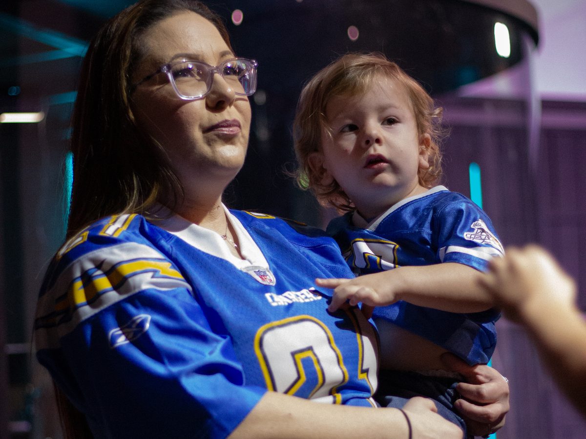 A mom holding her little boy in a football jersey on Draft Sunday